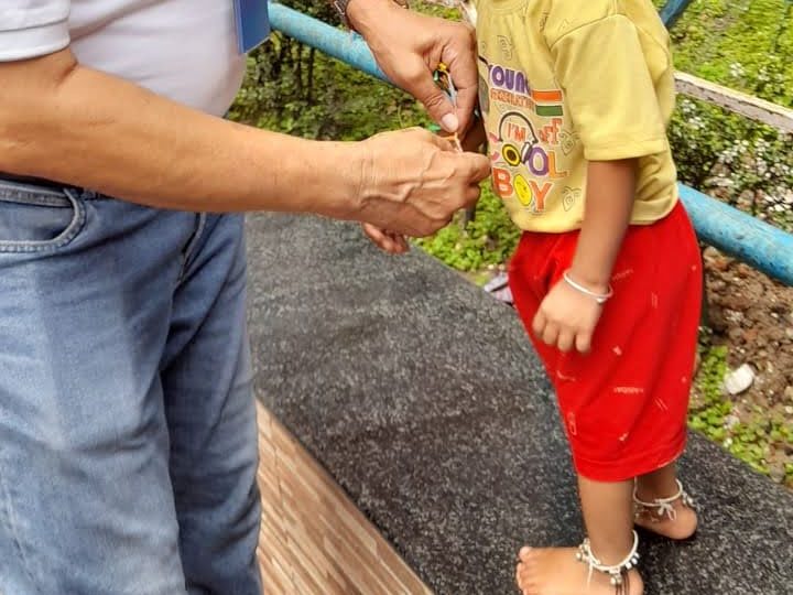 A member of TOREE tying a rakhi on a small child's wrist.