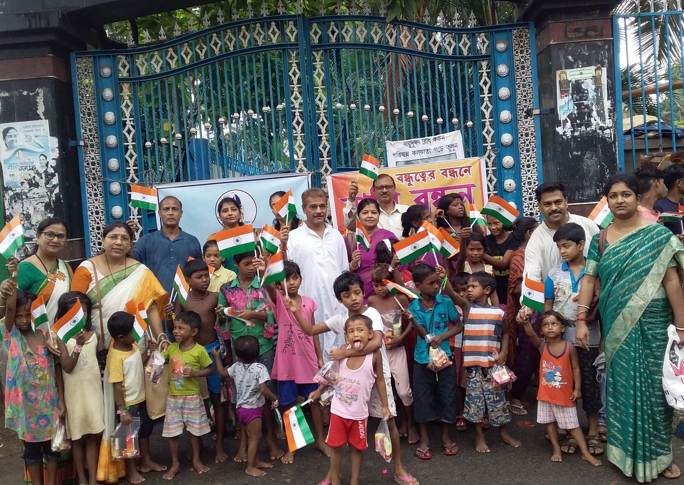 A large group of children and members holding national flags at an Independence Day celebration.