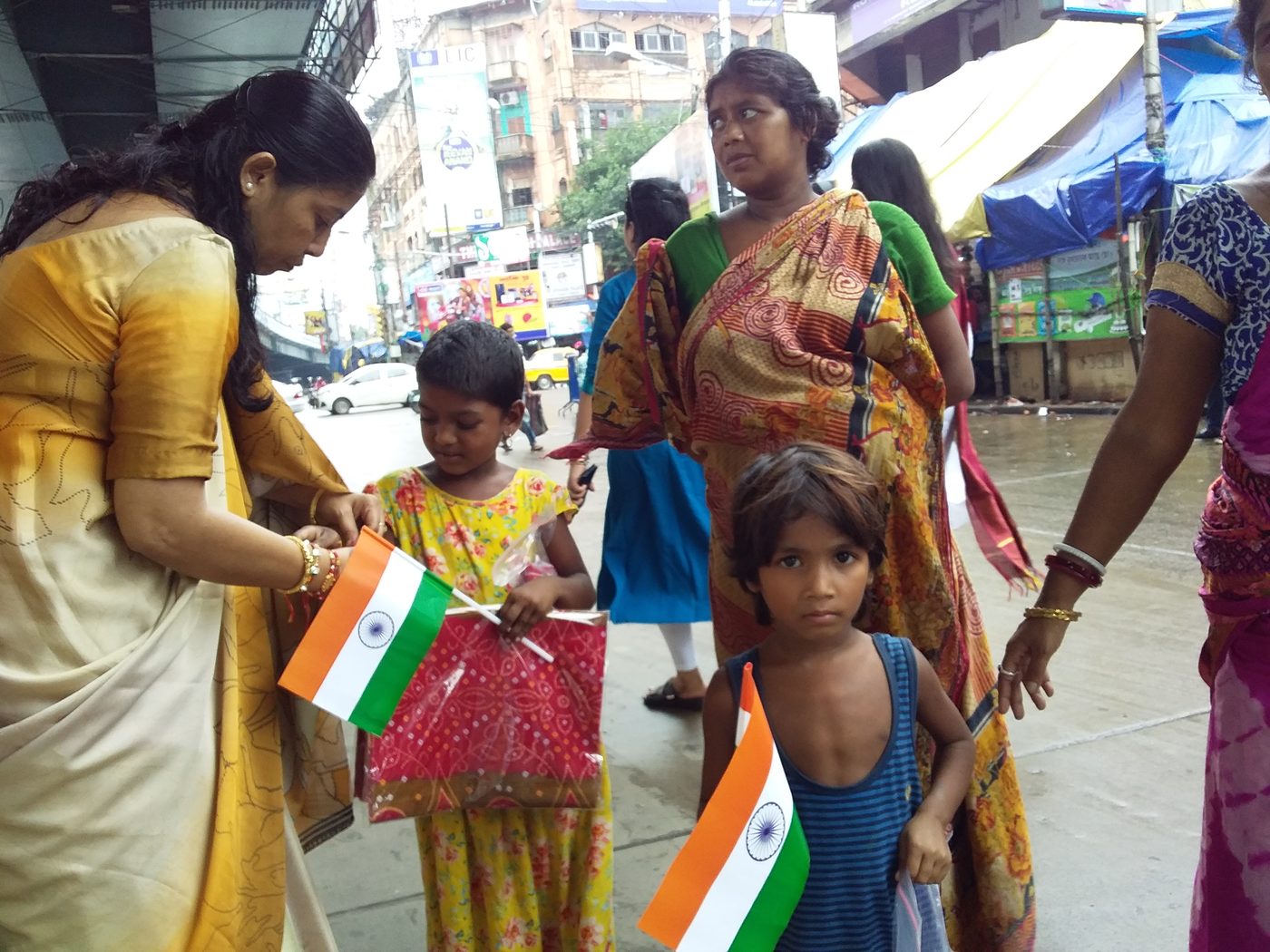 A member tying a rakhi on a child's wrist on a street in Kolkata.