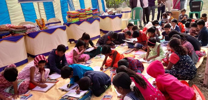 Rows of children bent over their drawings at a sit-and-draw competition, January 2025.