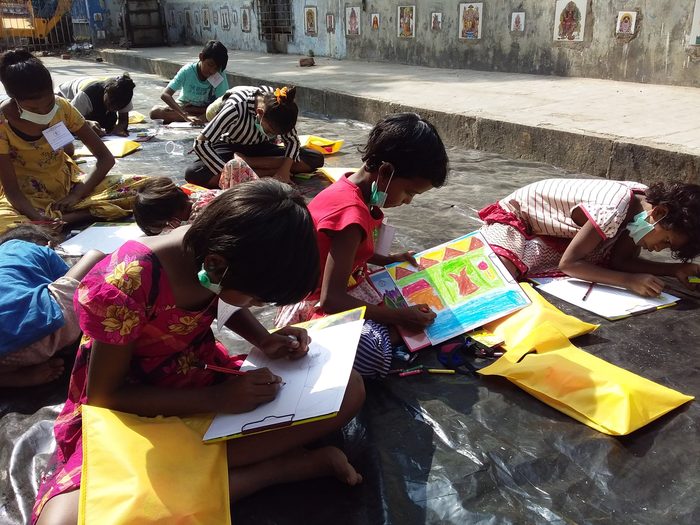 Children in masks drawing on sheets spread along a Kolkata street, January 2021.