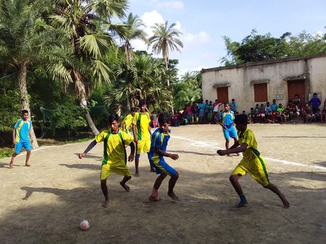 Young players contesting the ball at a village football tournament.