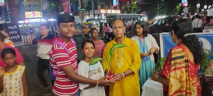 Two young passers-by receiving a potted plant during Rakhi Bandhan, August 2025.