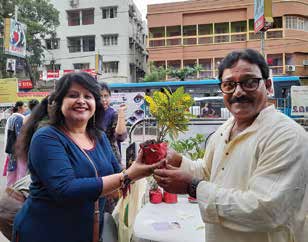 A small plant being gifted to a commuter during Rakhi Bandhan.