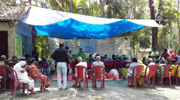 Villagers seated under an awning at a TOREE distribution camp.