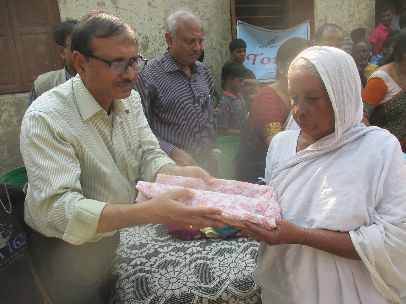 A member of TOREE handing garments to a woman at a distribution camp.